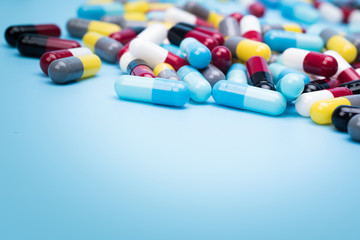 many scattered Colorful pills on blue background.