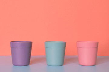 Three color plastic cup on pastel colors background.