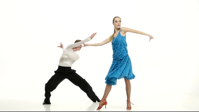 Couple of graceful dancers perform salsa on white studio background