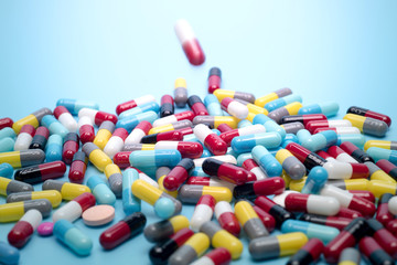 many scattered Colorful pills on blue background.