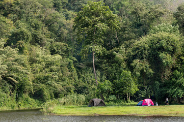 EASTERN, THAILAND: Camping on green grass beside lake and tropical evergreen forest in National Park