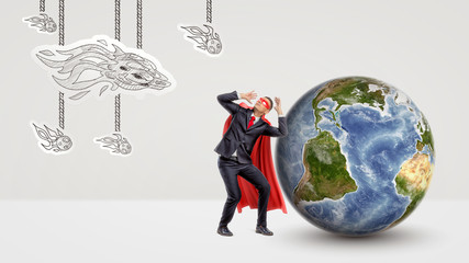 A scared businessman in a red cape cowering under an attack of paper comets with a globe behind him.