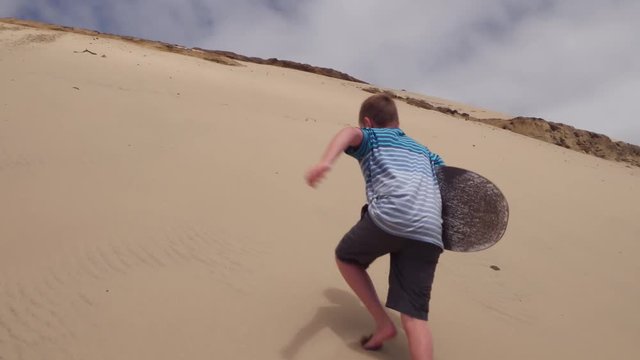 Boys walking with sandboards on dunes, Oregon