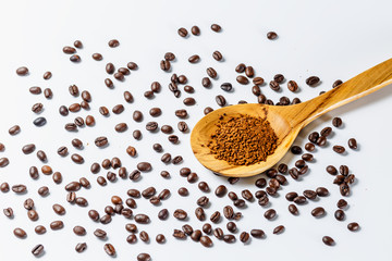 Roasted coffee beans and ground coffee in wooden spoon on white background