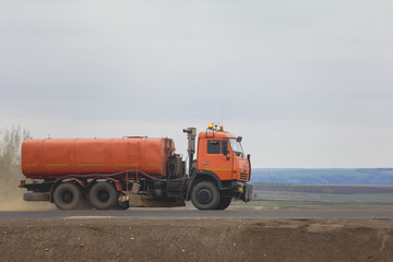 Obraz premium Construction machinery - watering truck at highway among field