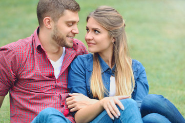 Romantic couple sitting on the grass and look into each other's eyes