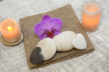 Stones for massage, candles and a flower of orchids on natural natural napkins, pleasant tones, a...