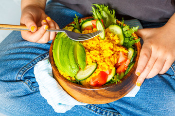 Сhild is eating a healthy salad with bulgur (couscous) and vegetables. Love for a healthy vegan food concept