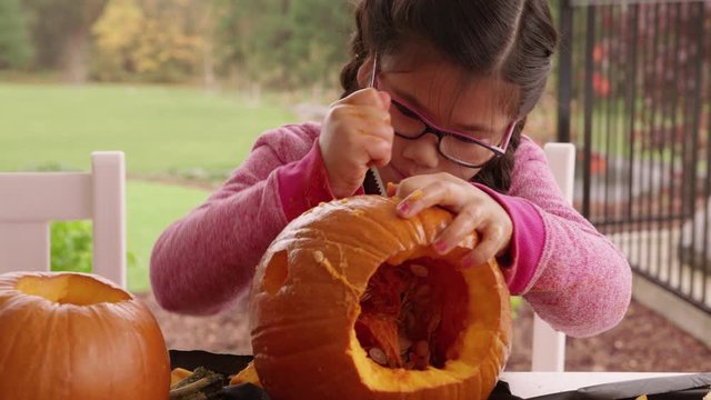 Young girl carving pumpkin for Halloween
