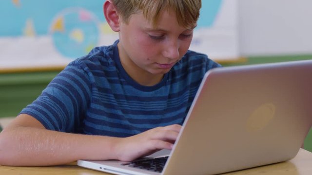 Boy in school classroom using laptop computer