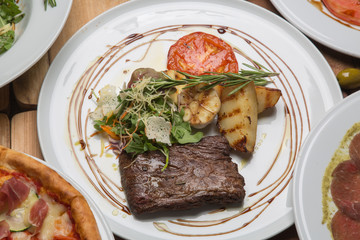 Toliet steak on a white plate surrounded by the other dishes on the table in the restaurant