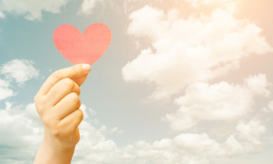 Paper heart in hand on cloud background