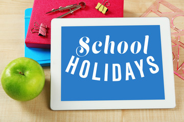 Tablet and school supplies on wooden table, closeup