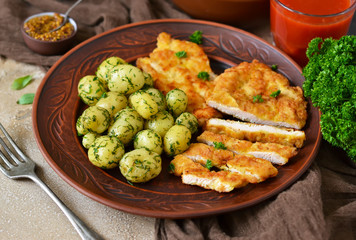 Schnitzel with potatoes and salad for lunch on a concrete background