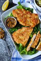 Schnitzel with pork on a cushion of spinach with mustard sauce on a concrete background