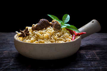 Instant noodles with pork soup in the clay pot on wooden background