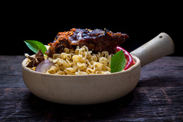 Instant noodles with roast pork spareribs in the clay pot on wooden background