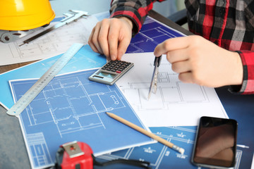 Male engineer hands working with blueprints on table