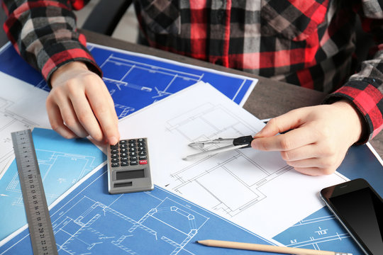 Male engineer hands working with blueprints on table