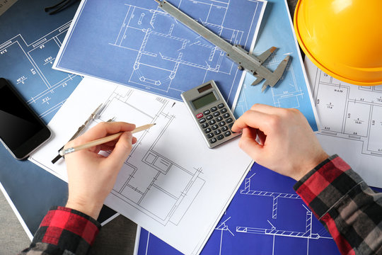 Male engineer hands working with blueprints on table