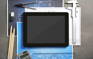 Tablet with blueprints and engineer equipment on table
