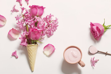 Flowers in a waffle cone with yogurt on white background