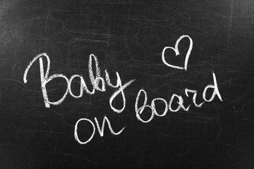 Words BABY ON BOARD written with chalk on blackboard