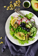 Vegan vegetable salad with flax seeds and olives on a black background