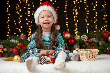 Fototapeta na wymiar child girl portrait in christmas decoration, happy emotions, winter holiday concept, dark background with illumination and boke lights