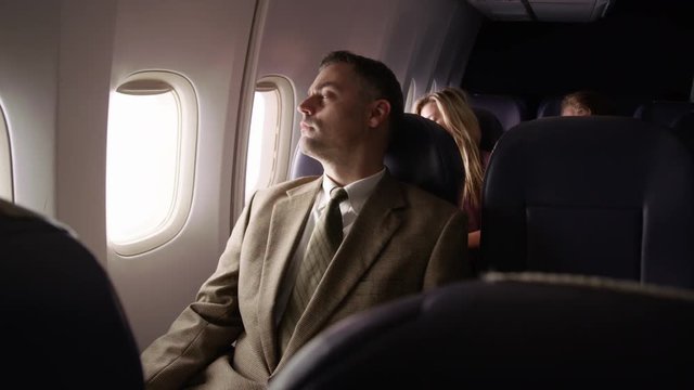 Man On Airplane Closes Window And Takes A Rest