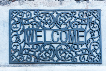 Welcome mat on the cement floor background.