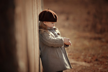 .A cute little sad girl stands by the fence.Thoughts, dreaming, hurt, sadness, sunlight.