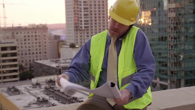 Construction manager on rooftop using looking at plans