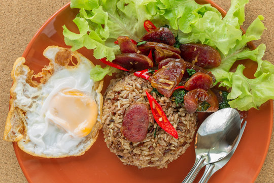 Top view of spicy basil thai food, black, brown rice with pork sausage and fried egg.