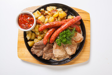 grilled sausages with potatoes, and roasted meat on a grill pan