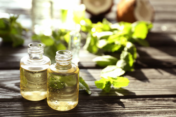 Perfume bottles and fresh mint on wooden table