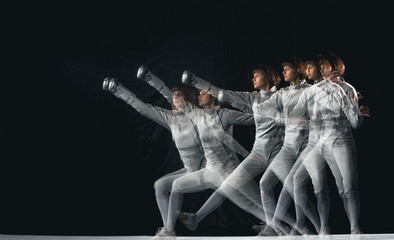 Full-length portrait of woman wearing white fencing costume on black