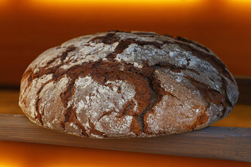 Loaf of fresh black rye bread out of oven close up
