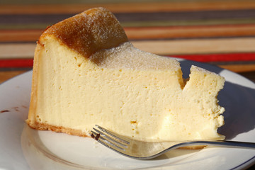 Slice of cheesecake on white plate with fork