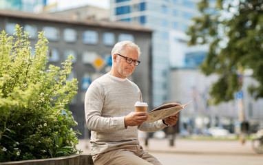 senior man reading newspaper and drinking coffee