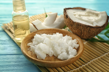 Plate with fresh coconut oil and half of nut on wooden table