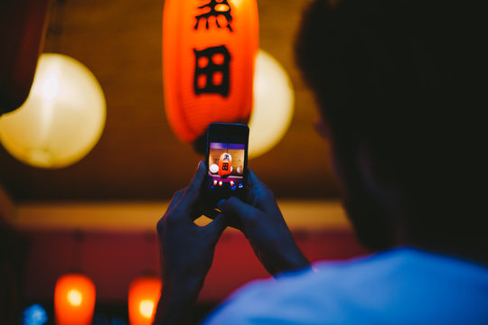 Young man making a picture of Japanese red lantern at night with mobile phone