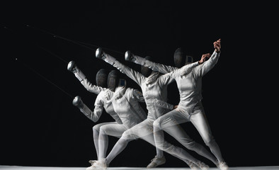 Full-length portrait of woman wearing white fencing costume on black