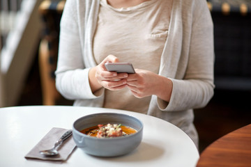 Obraz na płótnie Canvas woman with smartphone and pumpkin soup at cafe