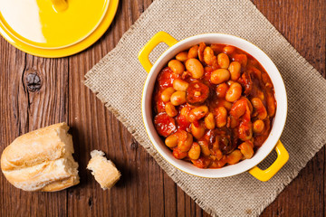 Baked beans in tomato sauce served in yellow, clay bowls.