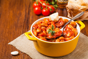 Baked beans in tomato sauce served in yellow, clay bowls.