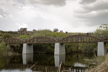 Old wooden bridge rises a river on a quiet and lonely cloudy day
