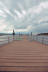 Naklejka premium It is very cloudy on the beach and no tourists are sunbathing on the pier. The sunshades are closed.