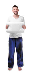 Young happy man in pajamas holding orthopedic pillow on white background