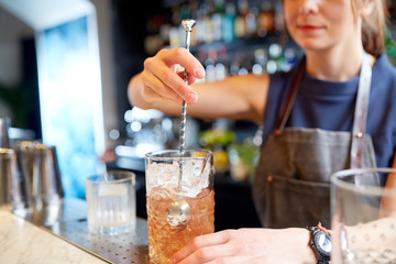 bartender with cocktail stirrer and glass at bar